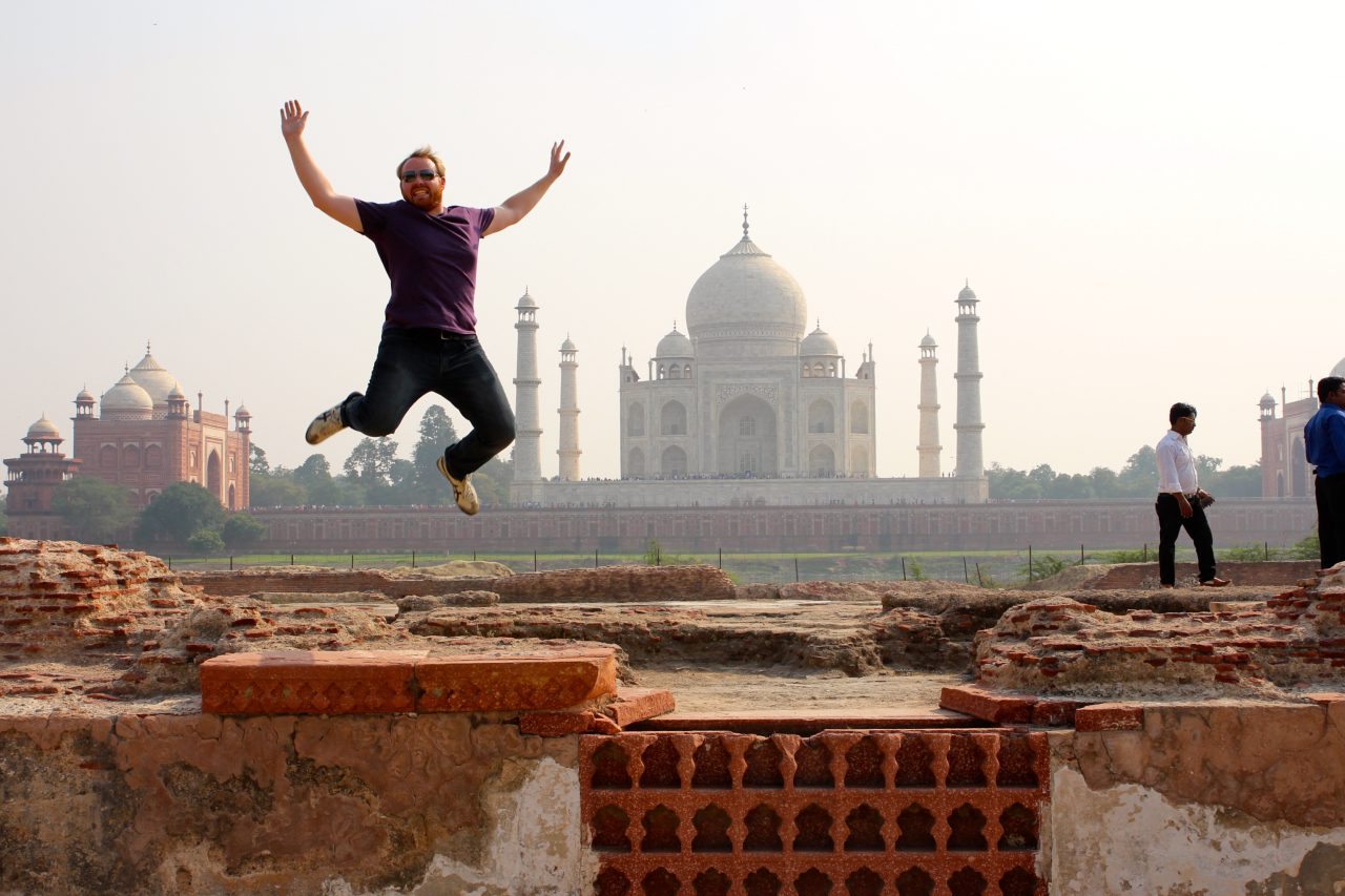 India travel photo of man jumping in front of Taj Mahal