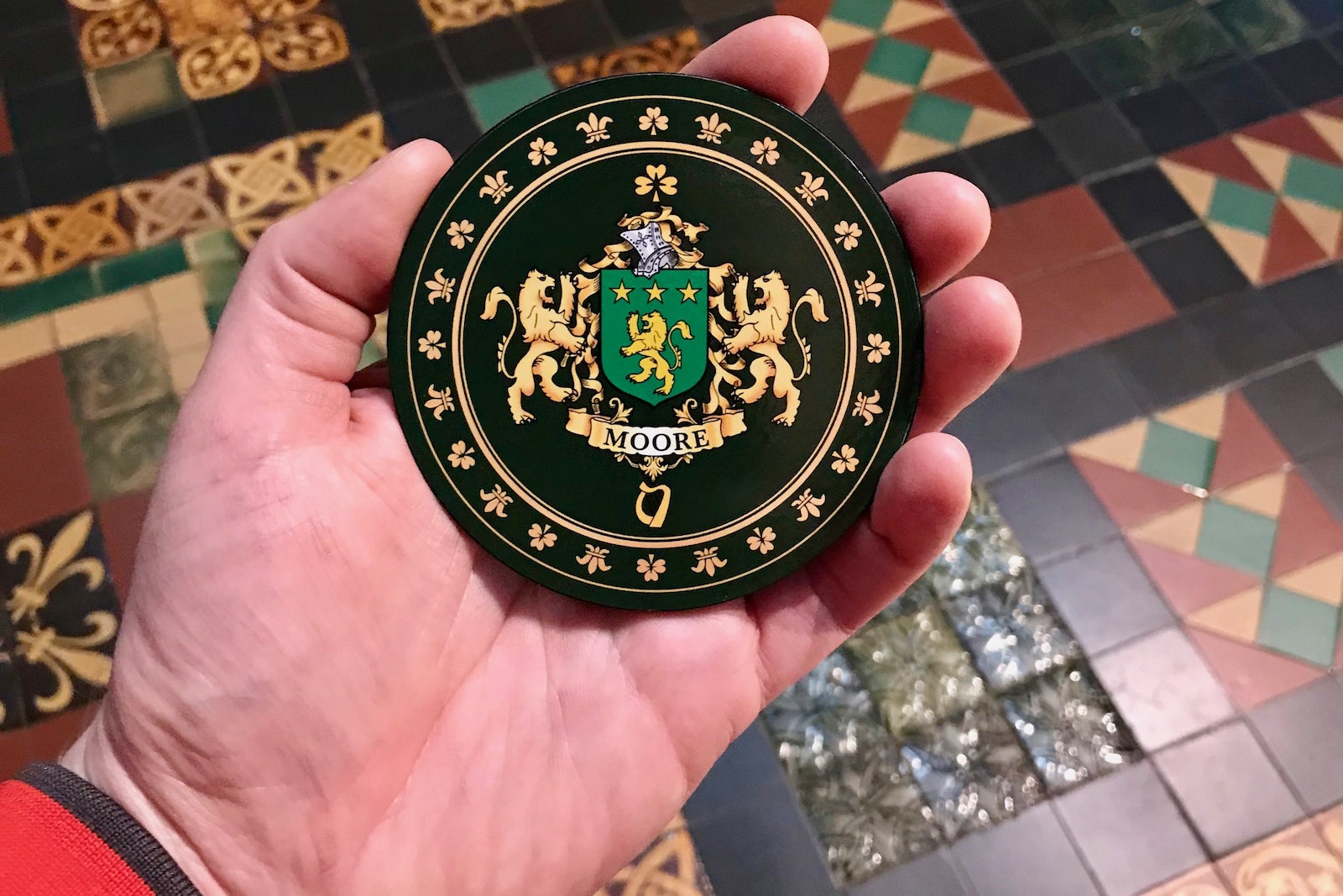 Judson holds the Irsh family crest for Moore. Two golden lions flank a green shield with three golden stars and a golden lion on it