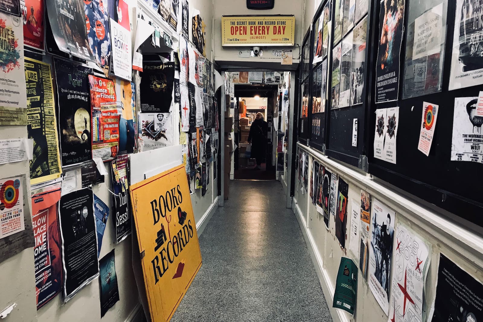 A long corridor with walls covered in posters and a bookshop at the end