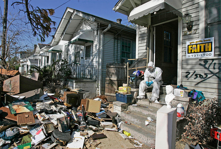 A man sits in front of his flooded house in New Orleans after Hurricane Katrina.